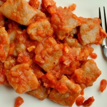 overhead view of gnocchi in a tomato, onion, and pancetta sauce on a white plate