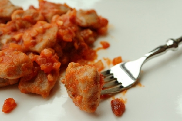 A closeup of a forkful of gnocchi in a tomato and pancetta sauce