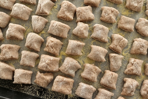 pillowing square gnocchi lined up on a cornmeal dusted tray