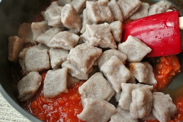 gnocchi after boiling added to a pan of tomato sauce