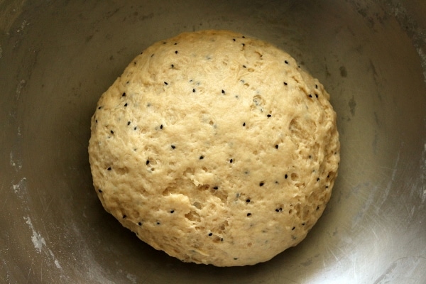 A close up of a bowl of dough with nigella seeds in it