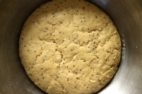 A close up of a bowl of dough with nigella seeds in it after rising