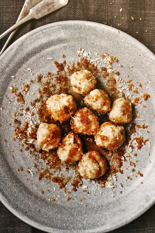 a plate of round gnocchi topped with bread crumbs