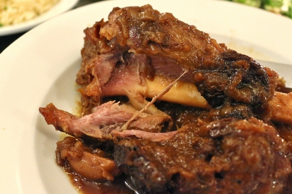 a closeup of meat pulled off the bone of a braised lamb shank