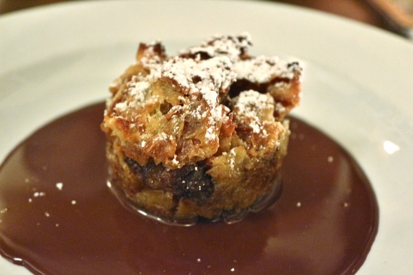 A piece of bread pudding served over a dark sauce on a plate