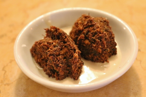 a halved falafel patty served in a small plate with tahini