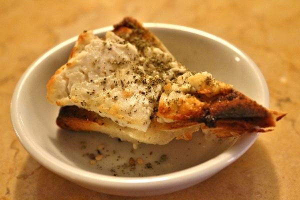 a small piece of za\'atar feta pizza on a white plate