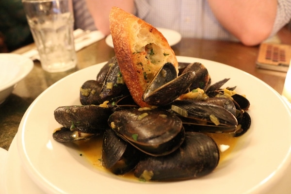 A plate of mussels topped with a piece of crusty bread