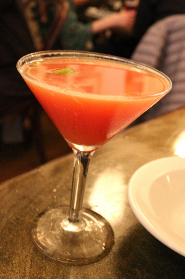 A close up of a cocktail glass filled with a red drink