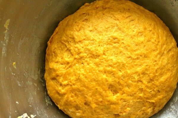 A closeup of bright golden yellow dough in a metal mixing bowl