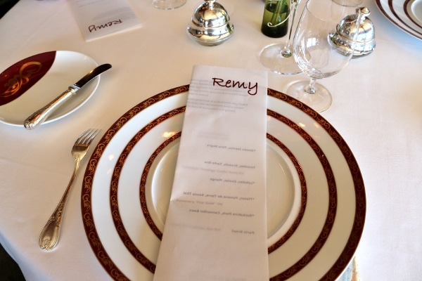 a folded menu on top of a plate on a restaurant table setting