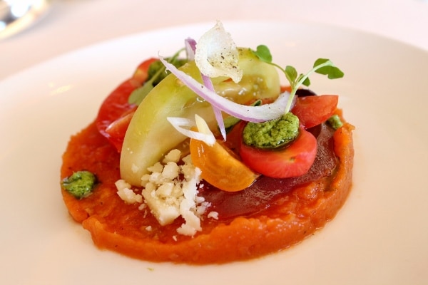 closeup of a plate of heirloom tomatoes with dollops of pesto