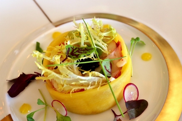 an elegant looking salad wrapped with slices of mango