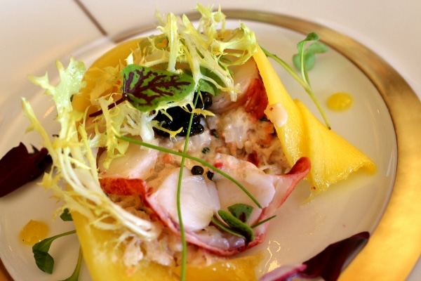 a half eaten plate of seafood salad wrapped with slices of mango