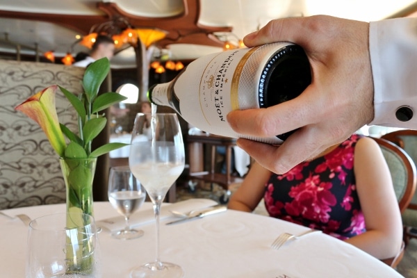 a hand pouring Champagne into a glass on a table