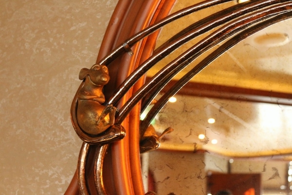 a closeup of a metal Ratatouille figurine on the edge of a mirror