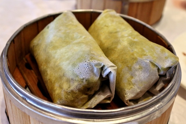 two leaf-wrapped packages in a bamboo steamer basket