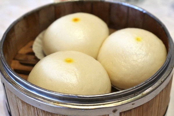 steamed egg custard buns in a bamboo steamer basket