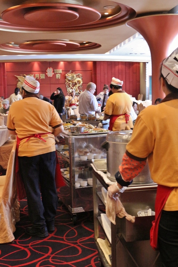 A group of woman pushing dim sum carts through a restaurant