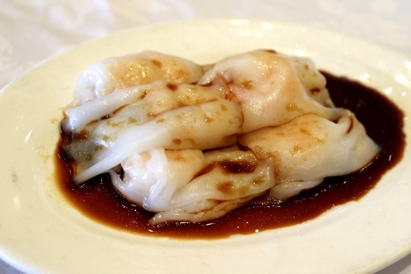 rice noodle rolls on a plate topped with soy sauce