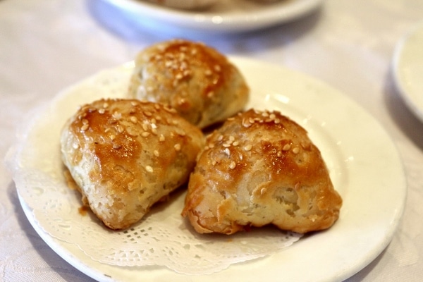 A closeup of a plate of sesame-topped flaky pastries