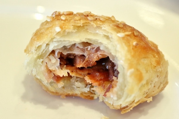 a half-eaten flaky pastry filled with barbecue pork