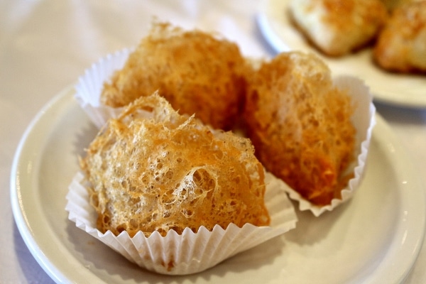 a plate of fried gossamer looking dumplings served on cupcake liners 