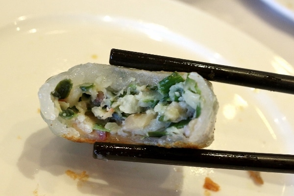 A close up of a half-eaten dumpling with green herb filling