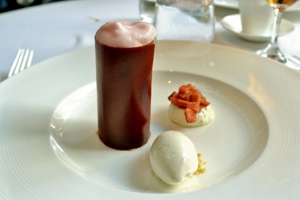 a tall cylinder topped with a foamy mixture, with ice cream on the side