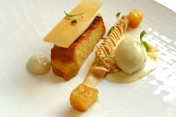 a rectangular piece of cake served with custard and ice cream