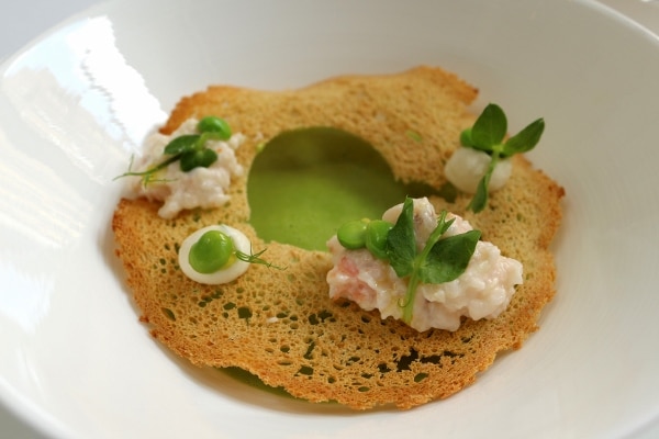 closeup of pea soup with a crispy cracker topping and dollops of shrimp custard