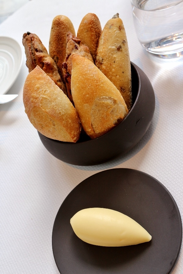 a modern looking bowl with small loaves of bread and a side of butter