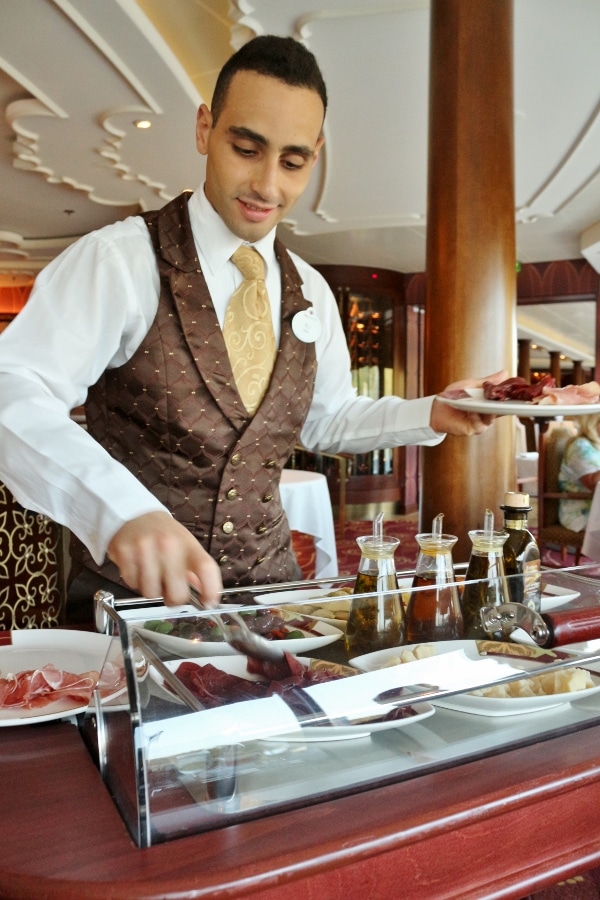 a man standing behind an antipasti cart