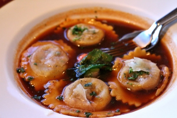 a closeup of a bowl of ravioli in a rich dark brown sauce