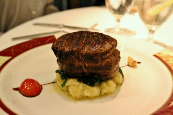 a filet mignon steak served over mashed potatoes on a plate