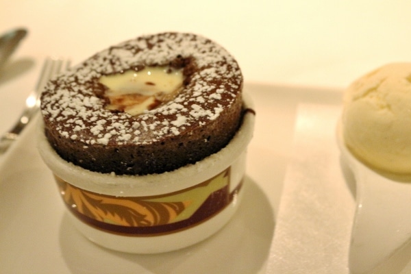 A closeup of a chocolate souffle topped with sauce