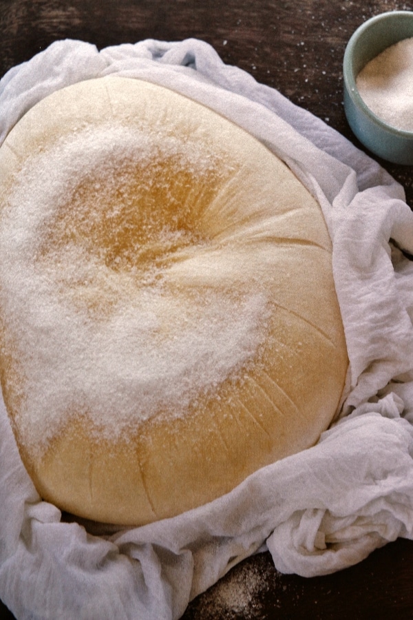 a free-form wheel of cheese partially wrapped in cheesecloth