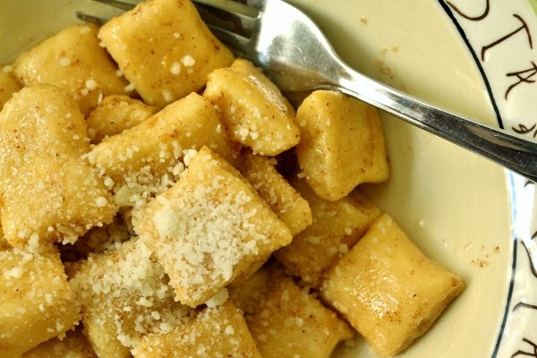 a closeup of a bowl of dunderi gnocchi in brown butter topped with grated cheese