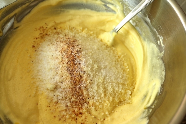 A closeup of a creamy mixture in a bowl with cheese and spices on top
