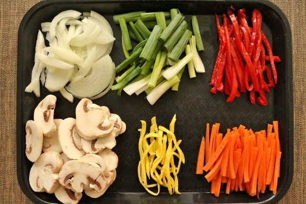a black tray topped with a variety of sliced colorful vegetables