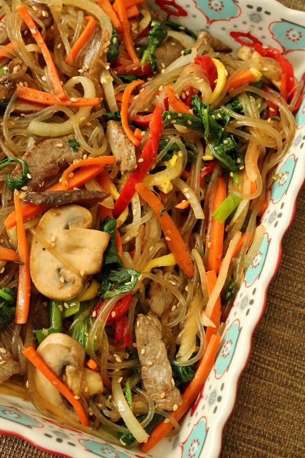 a dish of stir-fried sweet potato noodles with colorful vegetables and strips of beef