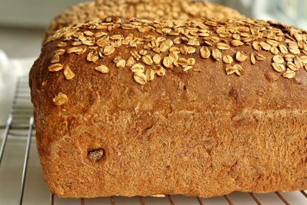 a side view of a loaf of whole wheat sandwich bread topped with oats