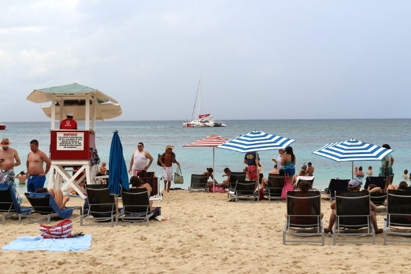 A group of people sitting at a beach with striped umbrellas