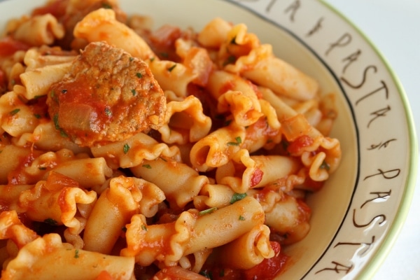a closeup of jerk chicken pasta with tomato sauce in a bowl