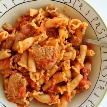 a shallow bowl of pasta with chicken in a tomato sauce
