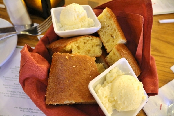 a basket of cornbread with scoops of butter on the side