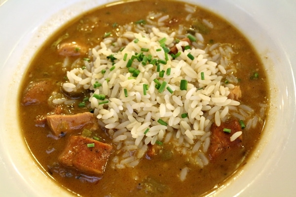 a bowl of gumbo with a pile of white rice in the center