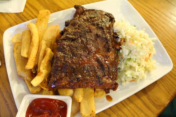 a rack of barbecue ribs on a plate with steak fries and coleslaw