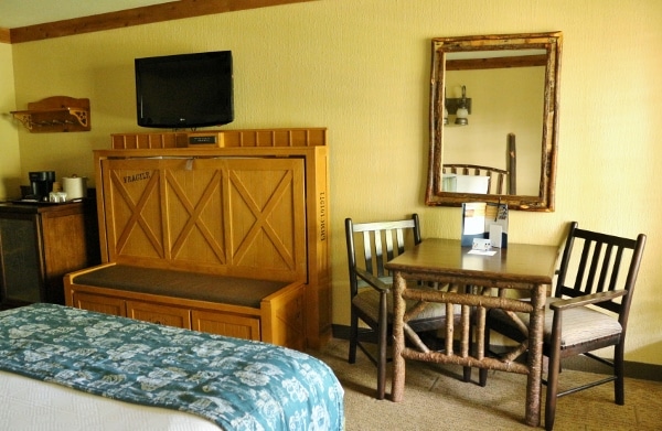 view of a table, chairs, mirror and television inside a hotel room