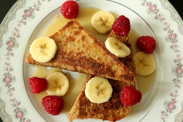 overhead view of french toast with sliced bananas and raspberries